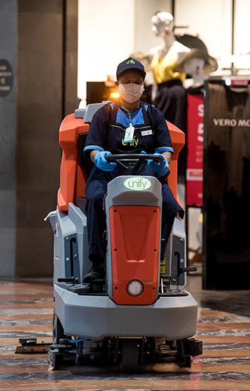 janitor operating a floor cleaning machine inside a shopping mall