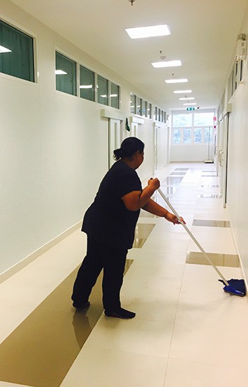 women janitor mopping floor in hallway of school building